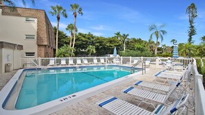 A rectangular swimming pool with a 3 FT 7 IN depth marker, surrounded by white lounge chairs with blue cushions, a white fence, and palm trees in the background. - Magnificent Oceanfront 2 BR Condo in Longboat Key - The Lookout (Florida)