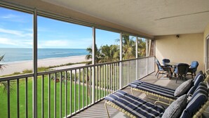 A balcony with a view of the beach, a seating area with cushions, and a table with chairs. - Magnificent Oceanfront 2 BR Condo in Longboat Key - The Lookout (Florida)