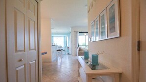 A hallway with a door, a table with a vase, and framed pictures on the wall. - Exquisite 2 BR / 2 BA Lake Front Condo In Lakewood National Golf Club - Precious Gem (Lakewood Ranch)
