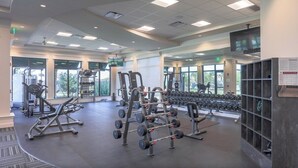 A modern gym with various weightlifting equipment, large windows, and a clean, organized layout. - Exquisite 2 BR / 2 BA Lake Front Condo In Lakewood National Golf Club - Precious Gem (Lakewood Ranch)
