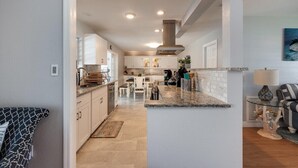 Una cocina moderna con armarios blancos, encimera de granito y una isla central.