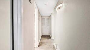 Un couloir étroit doté d’un plancher en bois de couleur claire et de murs blancs.