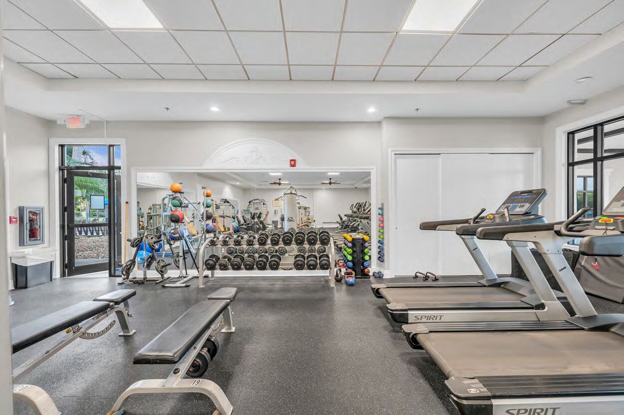 A gym with treadmills, weight machines, and a wall of dumbbells.