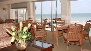 Een ruime woonkamer met een grote glazen deur die leidt naar een balkon met uitzicht op de oceaan.