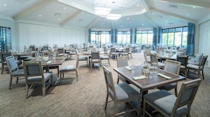 Une grande salle de conférence dotée de nombreuses tables et chaises, aménagée pour les réunions ou les repas.
