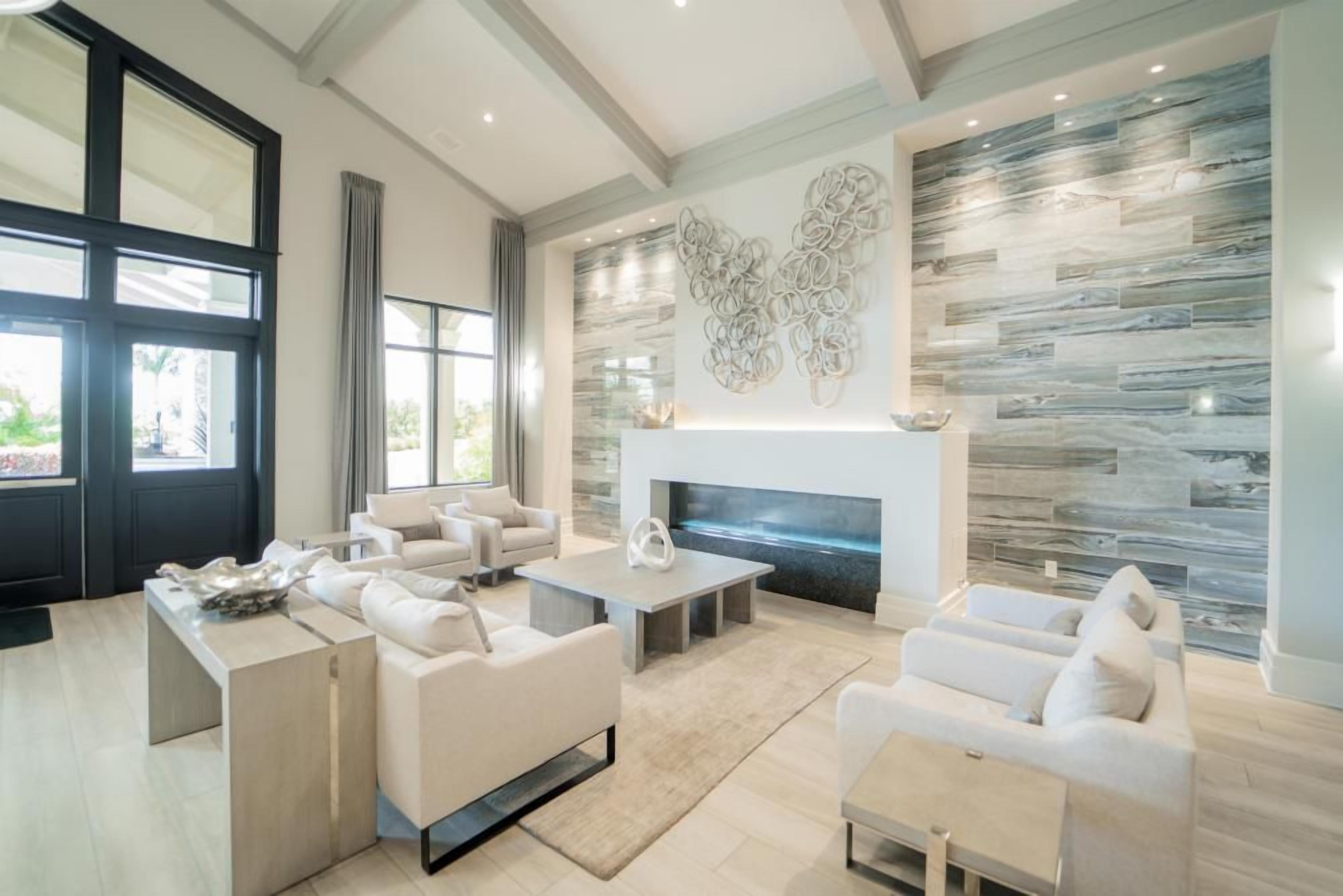 A modern living room with a fireplace, large windows, and a stone wall.