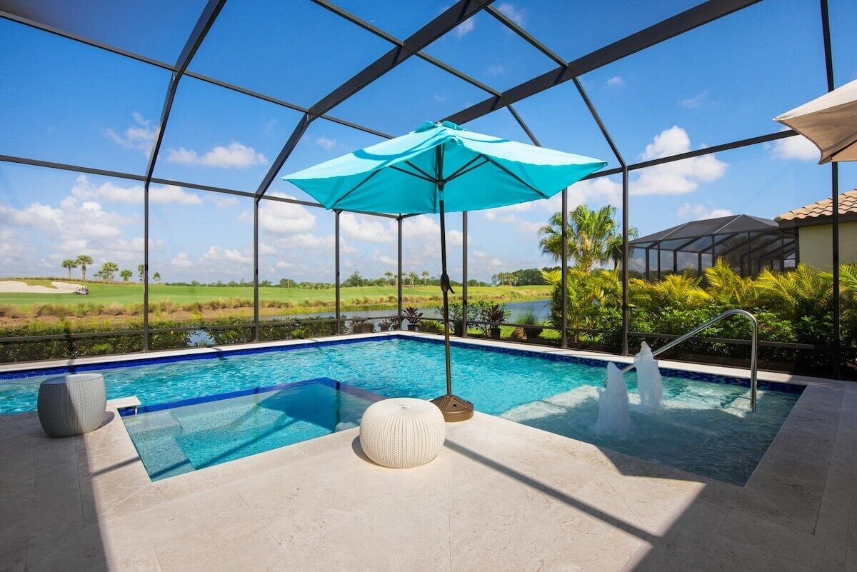Una piscina interior con vista despejada del paisaje circundante, una sombrilla azul y una fuente de agua.