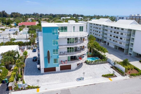 A multi-story hotel with a pool area, surrounded by palm trees and other buildings. - Luxury 4BR Siesta Key villa - Walk to the beach - Beach House Residences Unit 1 (Sarasota)