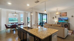 A spacious living area with a kitchen island, dining table, and seating. - Lakefront 2 BR/2 BA condo in Lakewood National Golf Club - Pearl in the Rough (Bradenton)