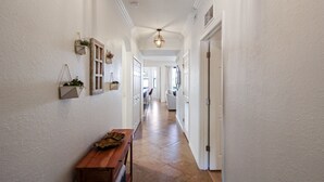 Un pasillo con un banco de madera, paredes blancas y un ventilador de techo.