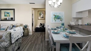 A modern living room with a sofa, dining table, and kitchen area.