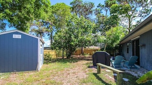 A backyard with a wooden deck, a barbecue grill, and a covered seating area with chairs. - Charming home near Manasota Key Beach Beach Heron (Venice)