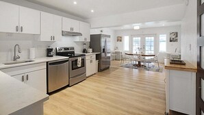 A modern kitchen with white cabinets, stainless steel appliances, and a wooden floor. - Bright and cozy pool home in Sarasota - Bali Poolside (Sarasota)