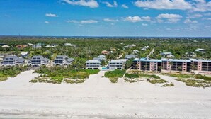 Vista aérea de un hotel costero con varias construcciones, una playa de arena y una vista despejada del océano.