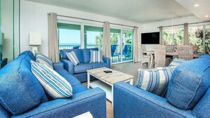 Una sala de estar moderna con sofás azules, una mesa de centro y un televisor.