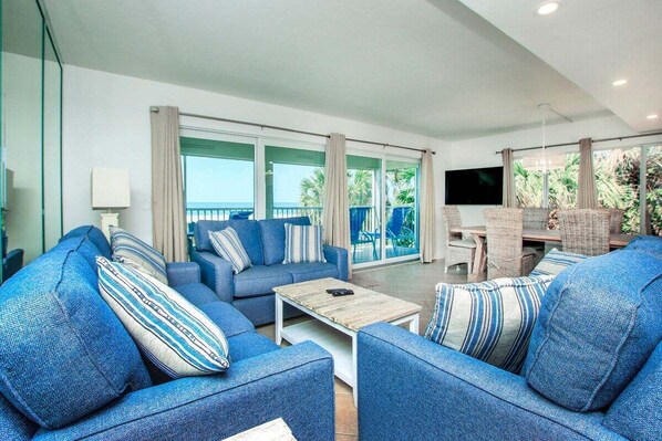 A modern living room with blue sofas, a coffee table, and a TV.