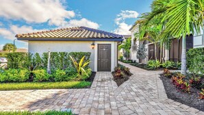 A residential property with a paved driveway leading to a house with a tiled roof and a dark front door. - Breathtaking 3 BR condo with lake views in Lakewood National Golf Club - Shades Of Summer (Lakewood Ranch)