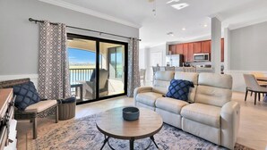 A spacious living room with a sofa, a coffee table, and a view to the outside. - Breathtaking 3 BR condo with lake views in Lakewood National Golf Club - Shades Of Summer (Lakewood Ranch)