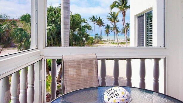 Ein Balkon mit Blick auf Palmen und einen Strand.