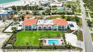 Ein Strandhotel mit Pool, Tennisplätzen und einer großen Rasenfläche.