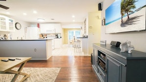 A modern kitchen with white cabinets, a wooden dining table, and a kitchen island. - 3 BR Pool Home In Nokomis - Close To Beaches - Tropical Escape (Nokomis)