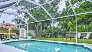A swimming pool with a glass enclosure, surrounded by outdoor furniture and lush greenery. - 3 BR Pool Home In Nokomis - Close To Beaches - Tropical Escape (Nokomis)