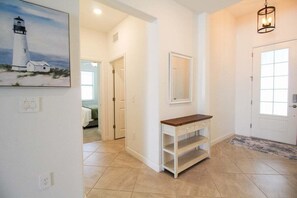 A hallway with a white console table, a mirror, and a painting of a lighthouse.