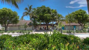 A hotel with a covered entrance, palm trees, and a clear blue sky. - Cozy 2BR condo on Lido Key, steps from the beach - Lido Del Mare (Sarasota)