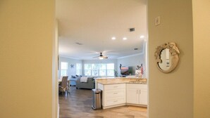 A spacious kitchen with a central island, a dining area with a sofa, and a ceiling fan.