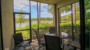 A sunroom with a glass wall, a ceiling fan, and a table with chairs. - Exclusive 2 BR Lakefront Condo in Lakewood National - The Duffers Retreat (Lakewood Ranch)
