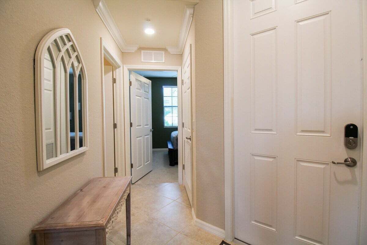 A hallway with a wooden bench, white doors, and a window with a decorative frame.