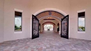 A spacious hallway with a tiled floor and arched ceilings, leading to a set of double doors. - Exclusive 2 BR Lakefront Condo in Lakewood National - The Duffers Retreat (Lakewood Ranch)
