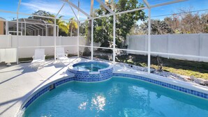 A swimming pool with a hot tub, surrounded by a white fence and a covered patio area with chairs. - Luxurious 4BR 2BA home with pool Bradenton My Great Escape (Bradenton)