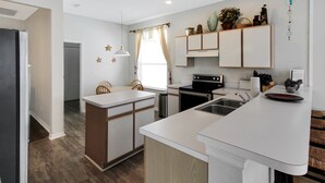 A modern kitchen with white cabinetry, a central island, a built-in oven, and a sink. - Luxurious 4BR 2BA home with pool Bradenton My Great Escape (Bradenton)