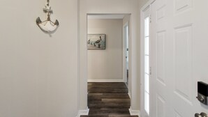 A hallway with a wooden floor, white walls, and a door on the right. - Luxurious 4BR 2BA home with pool Bradenton My Great Escape (Bradenton)