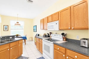 A kitchen with wooden cabinets, a white stove, a microwave, and a toaster. - Stunning 3BR lakefront - Pool home in Palmetto - Cranes Galore (Palmetto)