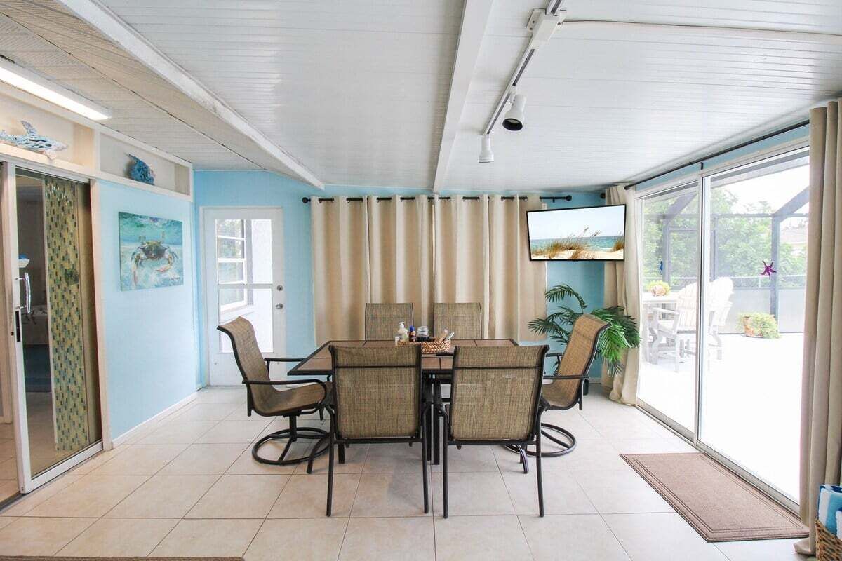 A dining area with a table and chairs, a television, and a view of the outdoors.