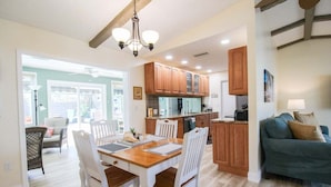 A spacious living area with a wooden dining table, white chairs, a blue sofa, and wooden cabinets. - Gorgeous 2BR 2BA Private Pool Home Near Siesta Key Sweet Pineapple (Sarasota)