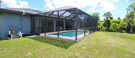 A house with a covered outdoor swimming pool and a screened porch.