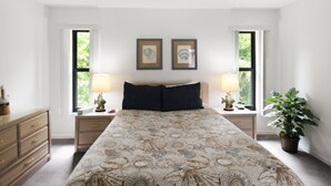 A bedroom with a large bed, two bedside tables with lamps, a dresser, and two framed pictures on the wall. - Relaxing 2BR - Pool home close to attractions - Charlotte's Dream (Port Charlotte)