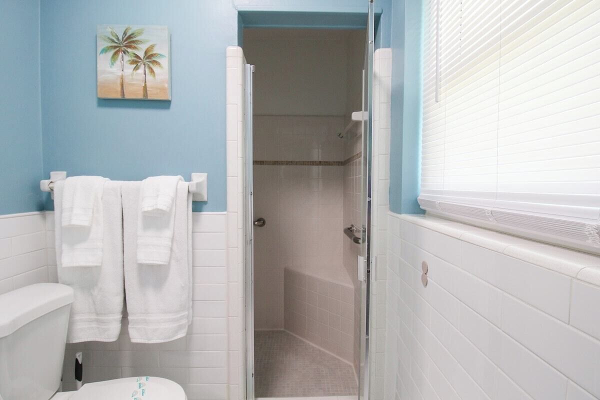 Un baño con inodoro, ducha y toallero con toallas.