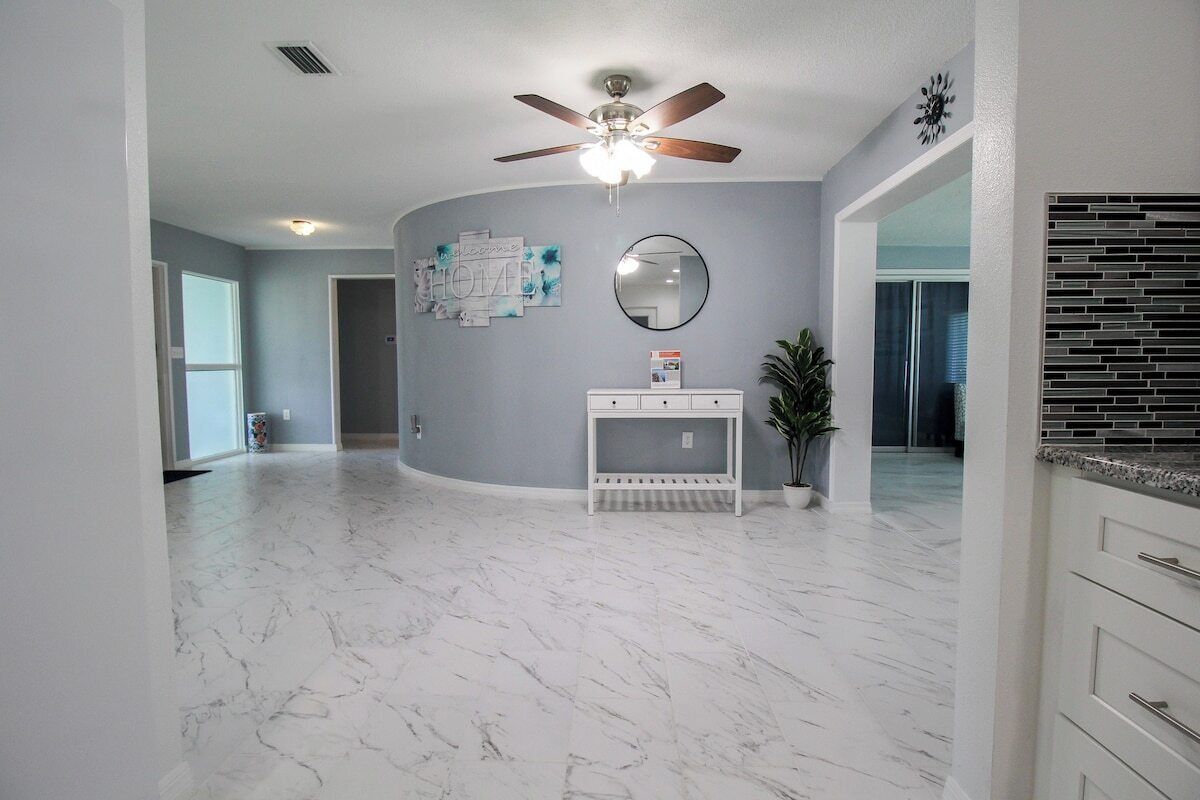 A spacious room with a ceiling fan, a marble floor, a white console table, and a potted plant.
