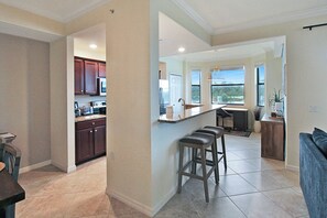 Una cocina amplia con armarios de madera oscura, una isla central con taburetes y vistas al exterior gracias a grandes ventanales.