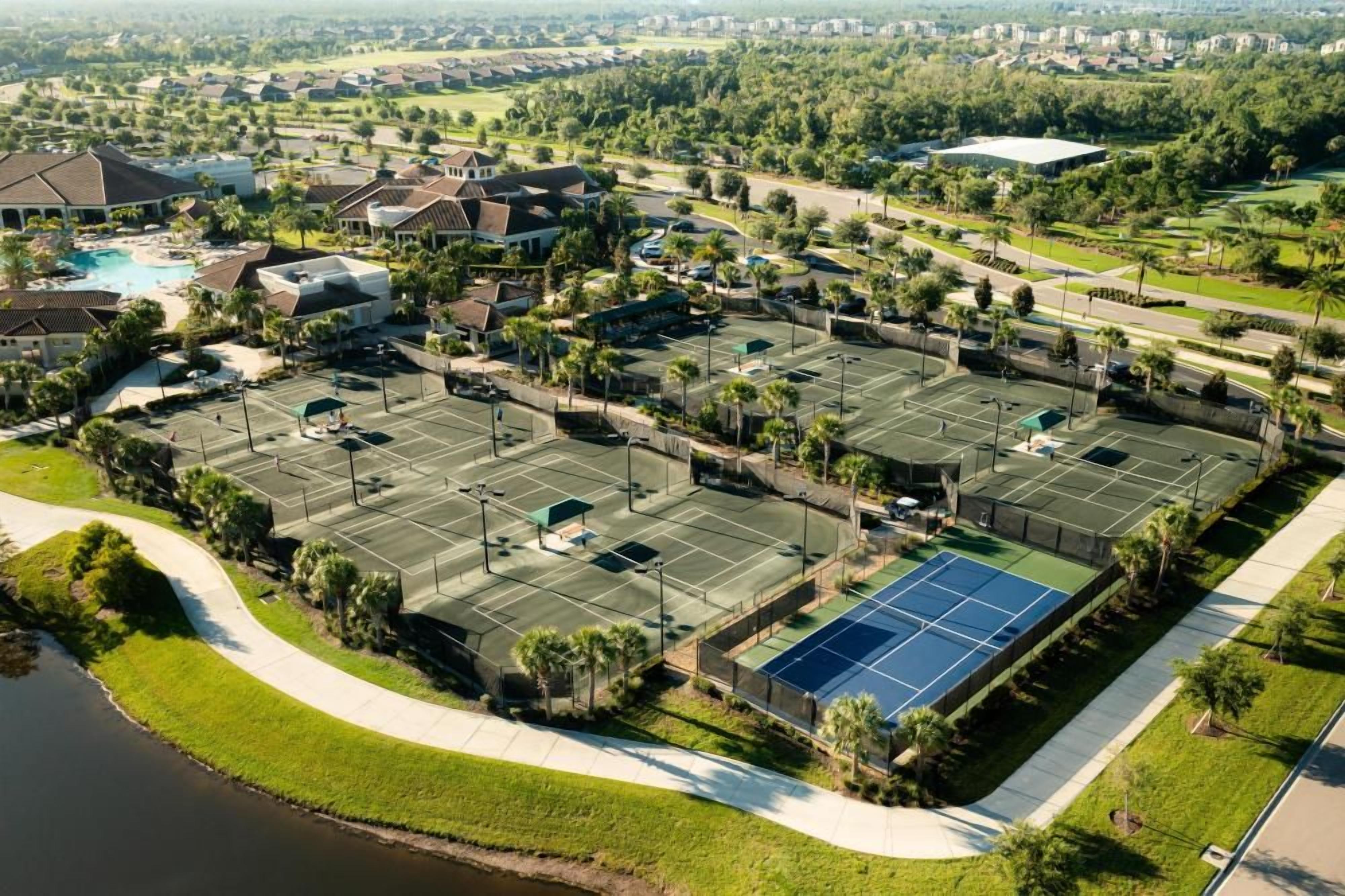 A residential area with multiple tennis courts, a swimming pool, and a large building.