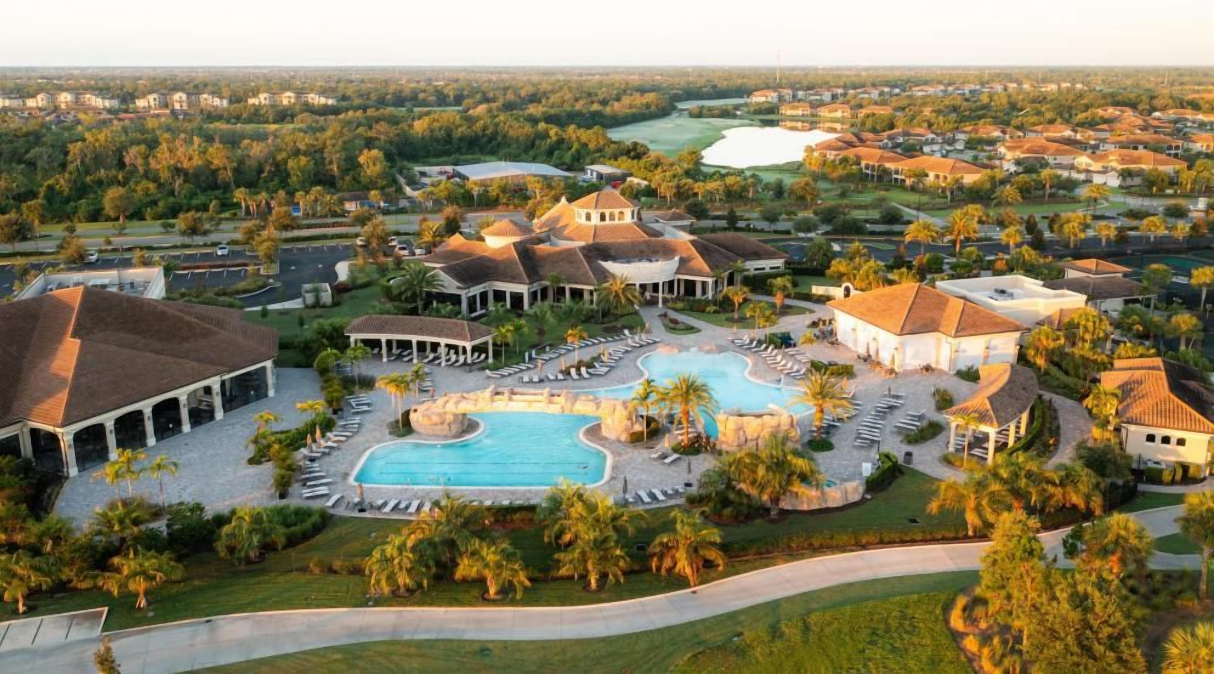 Un complexe hôtelier doté d’une grande piscine, de plusieurs bâtiments et d’un terrain de golf en arrière-plan.