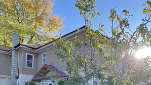 A two-story house with a red roof, a small front yard, and two red chairs. - A  Cozy studio unit in northern Wisconsin (Antigo)