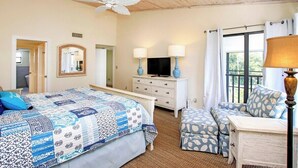 A bedroom with a large bed, a dresser, a television, and a window with curtains. - Spacious 3BR Retreat On Sanibel Island - Steps to the beach - Cyprina Beach #10 (Sanibel)