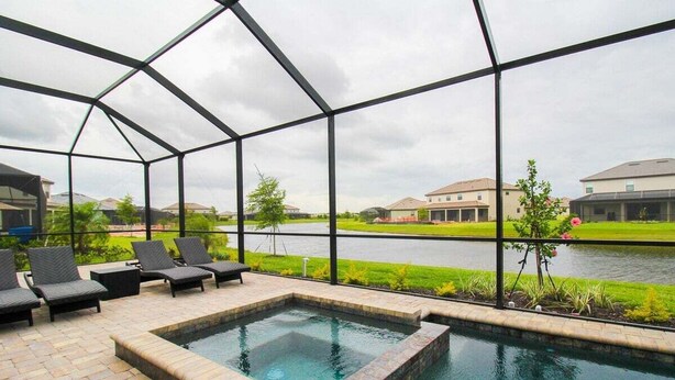 A pool area with a view of a river and buildings in the background. - Exquisite waterfront 3BR pool home in Lorraine Lakes - Grand Getaway (Bradenton)