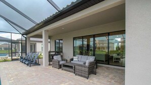 An outdoor patio with wicker furniture and a glass enclosure. - Exquisite waterfront 3BR pool home in Lorraine Lakes - Grand Getaway (Bradenton)