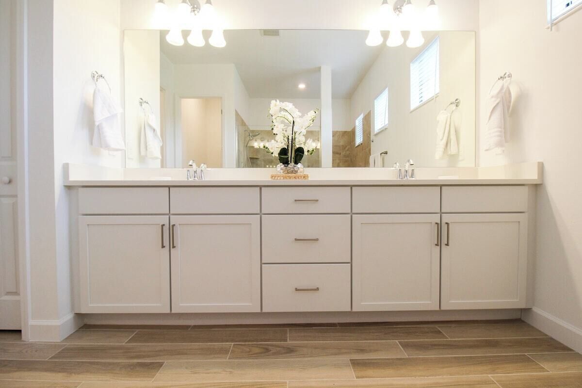 A bathroom with a large mirror, two sinks, and a vanity with drawers.